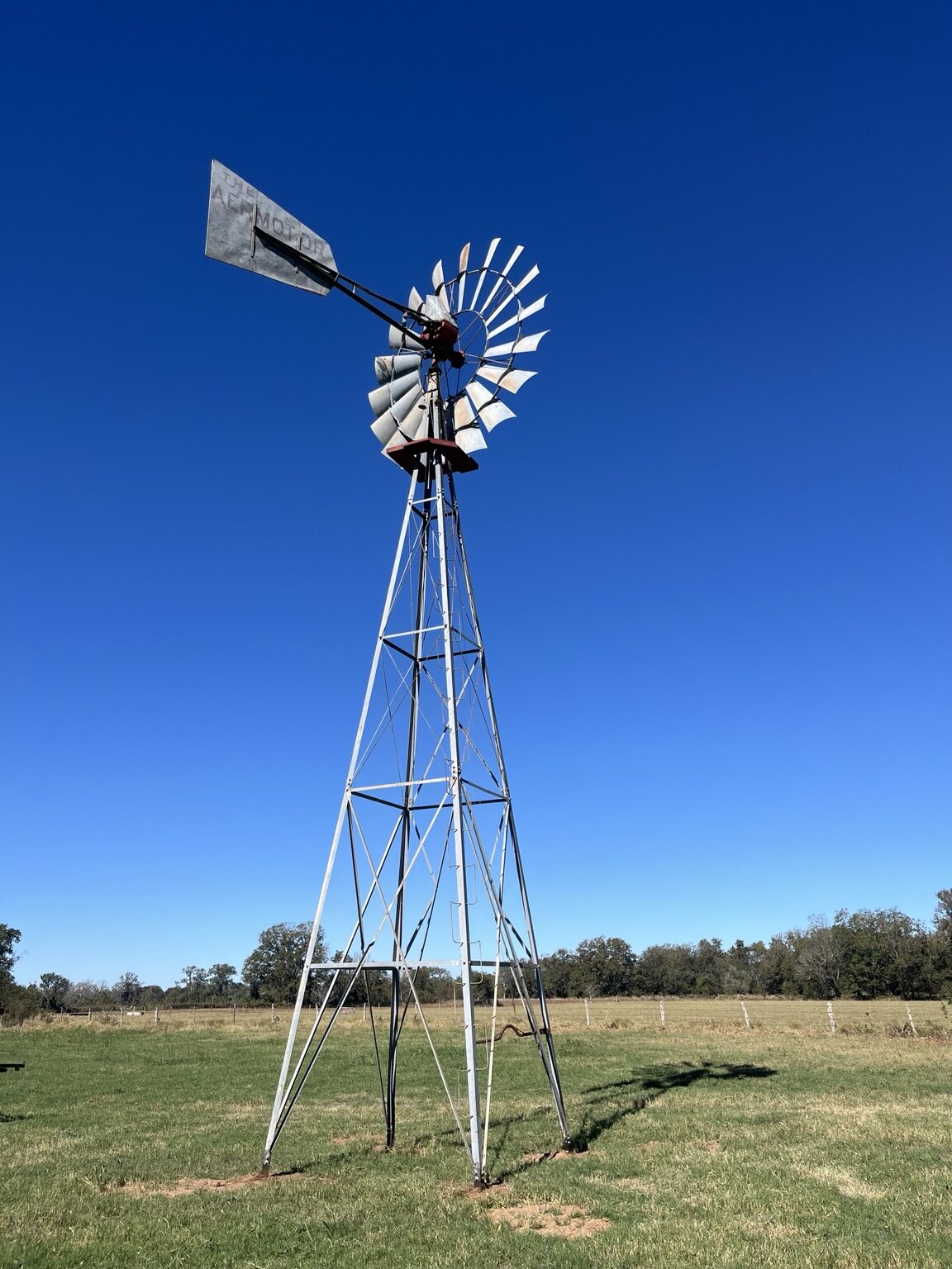 Completed windmill tower and wheel under a clear blue sky