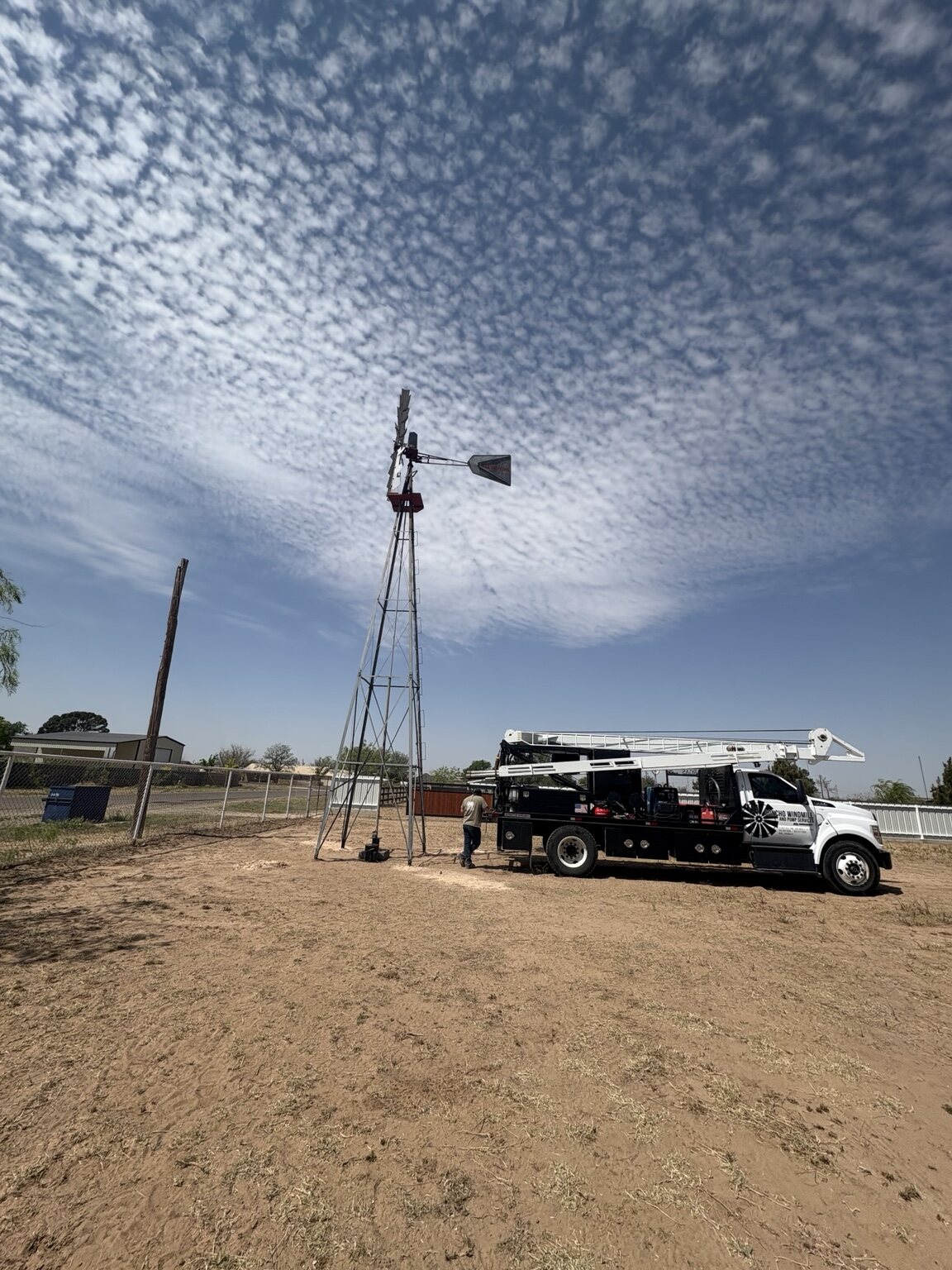 Concho Windmill truck and tower beneath a wide West Texas sky
