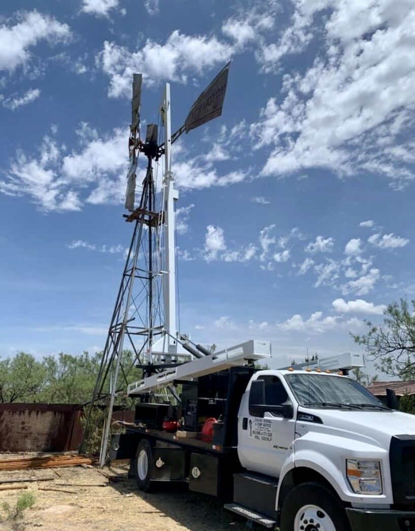 Crane truck servicing a tall windmill tower